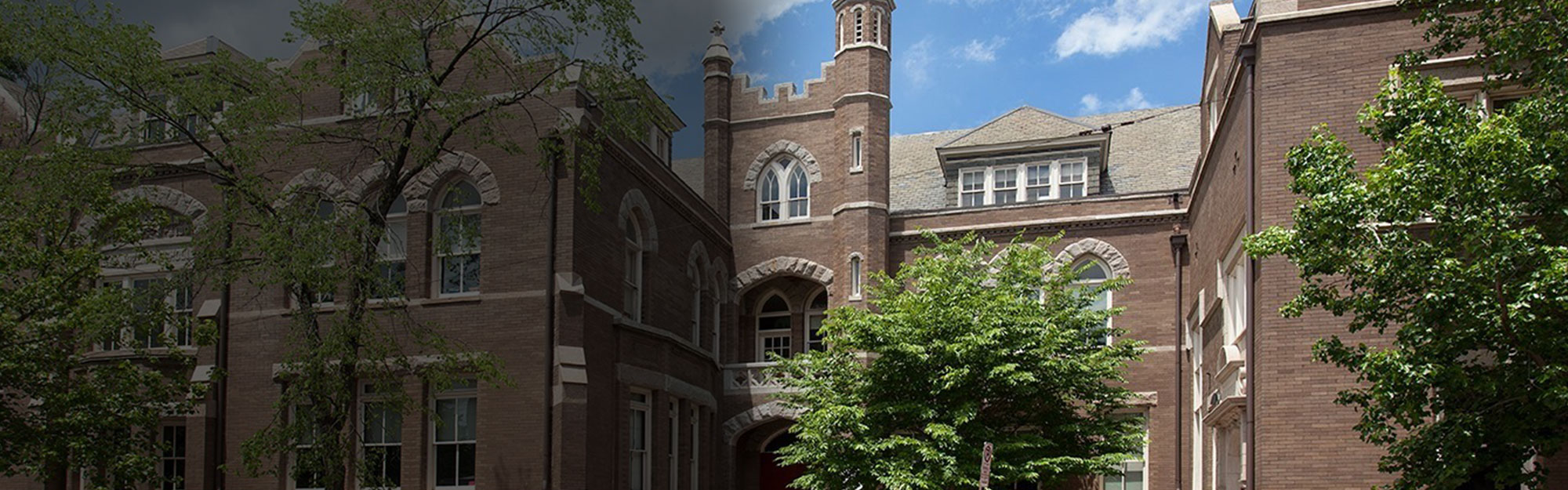 A photo of the St. Andrew's School building. There is a blue sky and green trees out front.