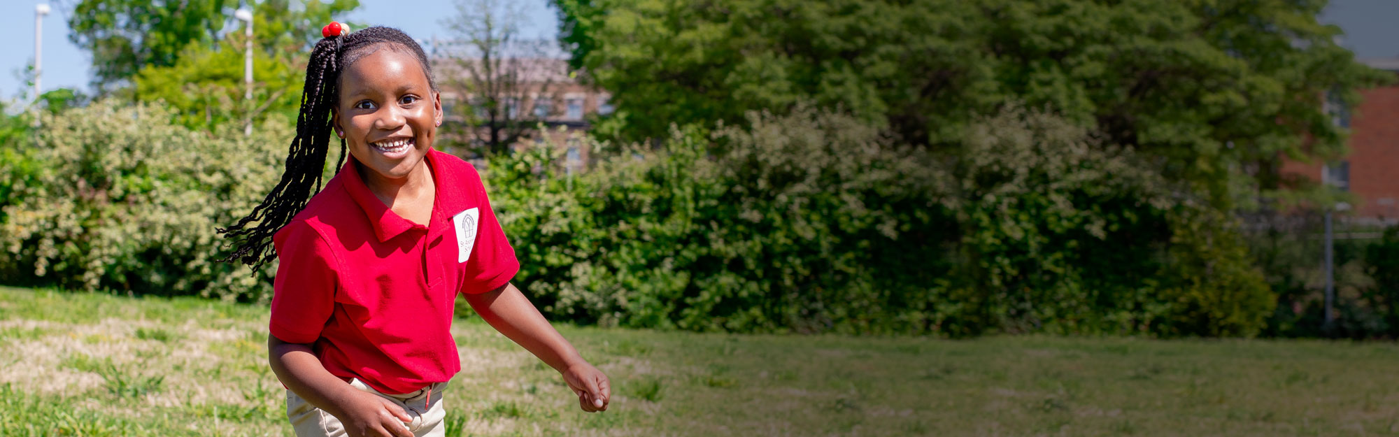 A smiling student plays outside.