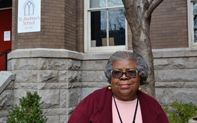 Volunteer Elnora Allen stands in front of the school.