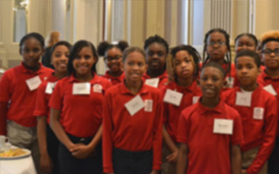 Students stand grouped together and smiling during a Fundraising Breakfast event.