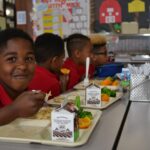 A student eating lunch in Baldwin Hall. He's looking at the camera and smiling.