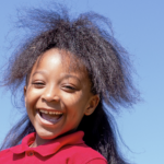 A smiling St. Andrew's School student against a blue sky.